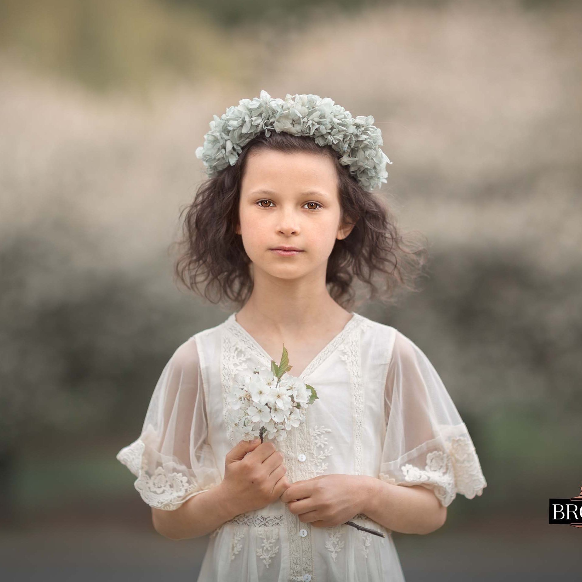 Jente i hvit kjole holder blomster