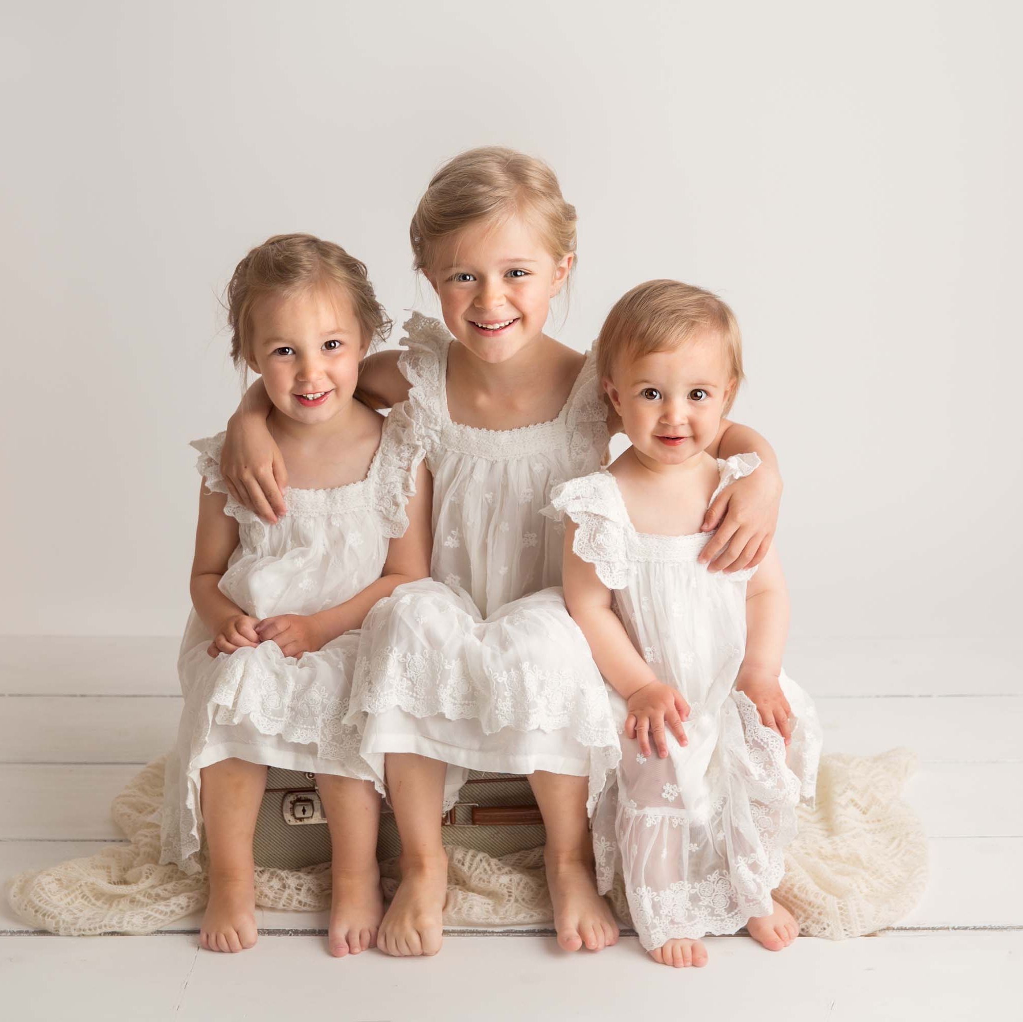Tre jenter i hvite kjoler søskenfotografering
