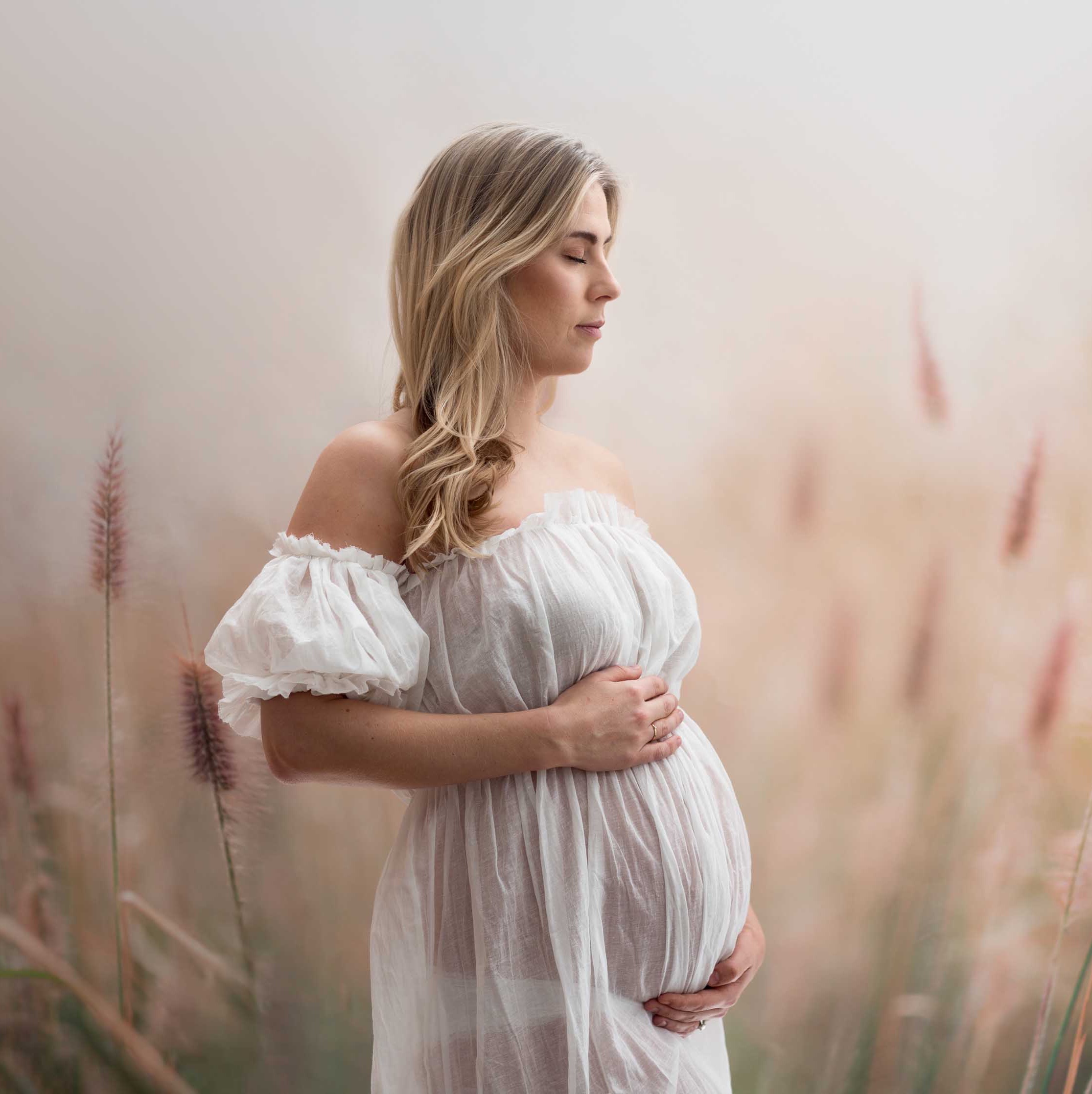 Gravid kvinne står i eng